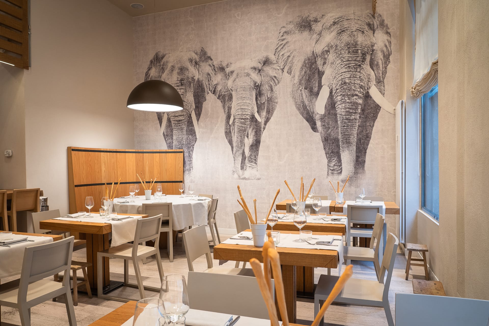 sala principale ristorante angolo 16 con tavoli apparecchiati e murales di elefanti
